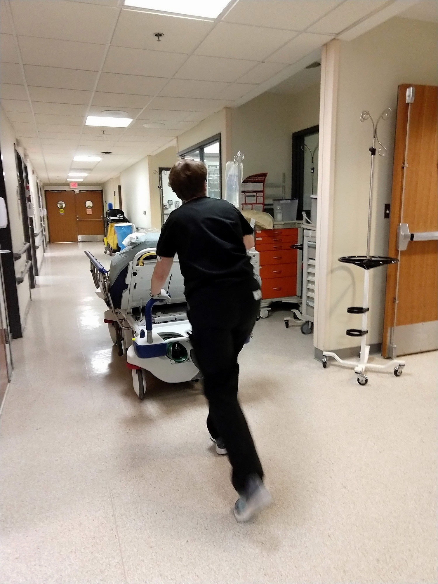 A patient being pushed on a gurney through a hospital ER Emergency Room hallway with an IV